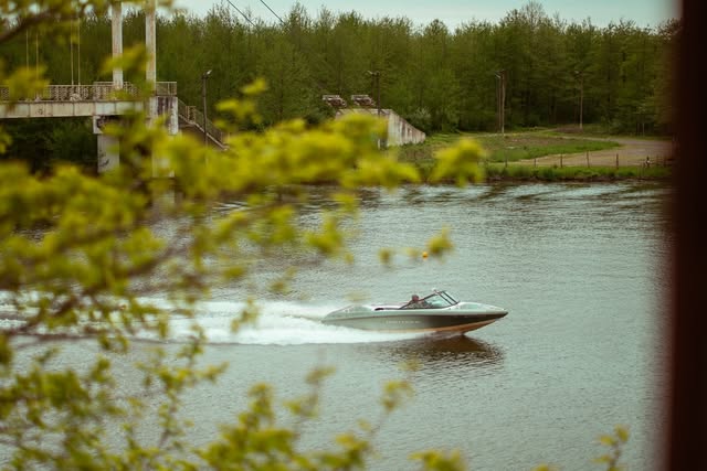 Speedboat cutting across Golden Lake framed by spring leaves